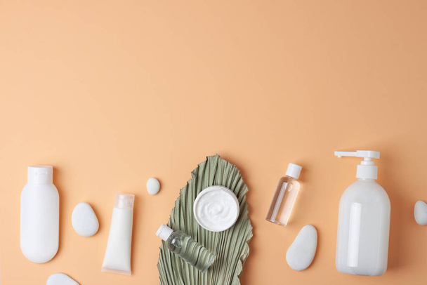 Pastel bej arka planda palmiye yaprağı olan kozmetik cilt bakımı ürünleri. Düz yat, boşluğu kopyala - Fotoğraf, Görsel