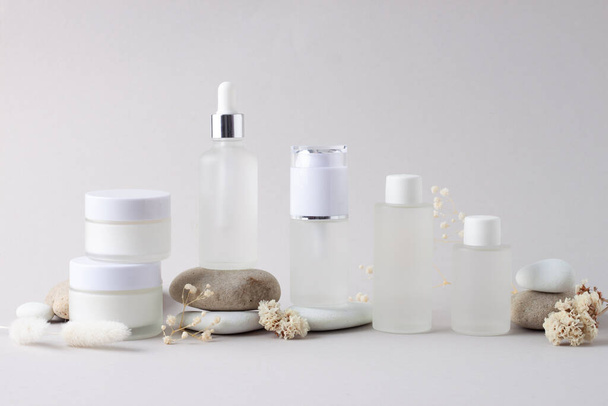 Kosmetische Hautpflegeprodukte mit Steinen und Blumen auf grauem Hintergrund. Nahaufnahme - Foto, Bild