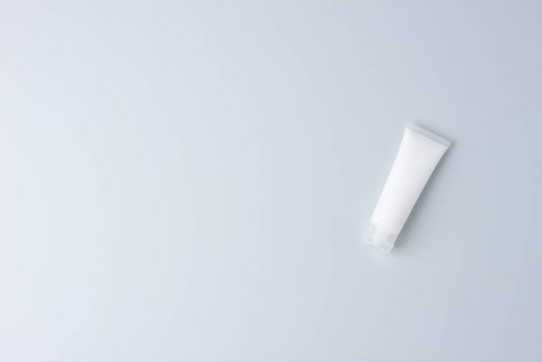 Cosmetic background with white tube of cosmetic cream on grey. Flat lay, copy spac - 写真・画像