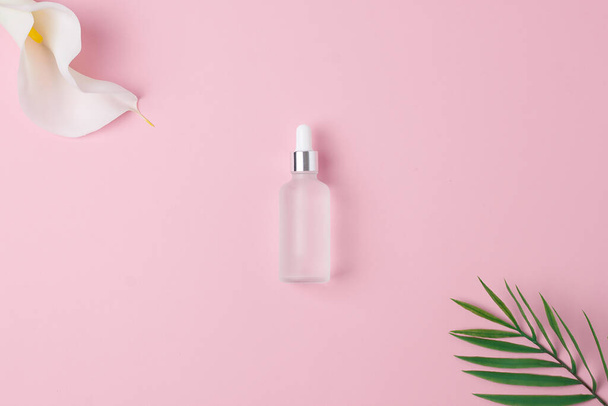 Cosmetic bottle on pink background with flowers, palm. Flat lay. - Photo, image