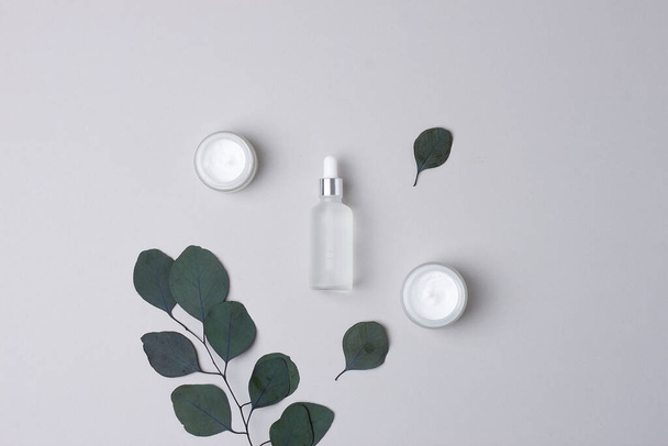Produtos cosméticos para cuidados da pele com eucalipto sobre fundo cinzento. Depósito plano - Foto, Imagem