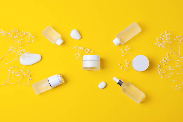 Cosmetic skin care products with flowers and stones on yellow background. Flat lay, copy space - Valokuva, kuva