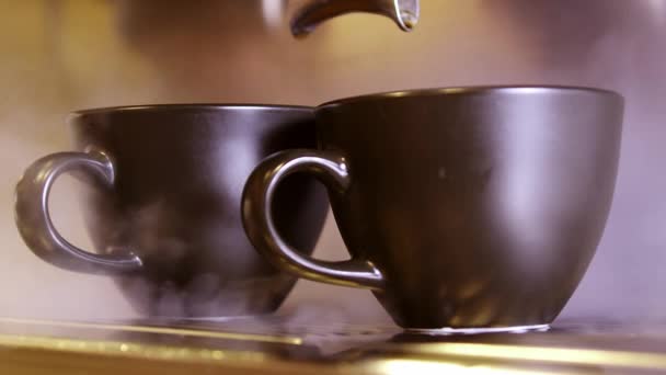 Кофеварка Бариста выдувает пар в черные чашки эспрессо - Кадры, видео