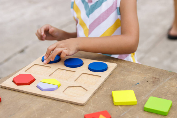 Little girl making colorful wooden puzzle in the street - Photo, image