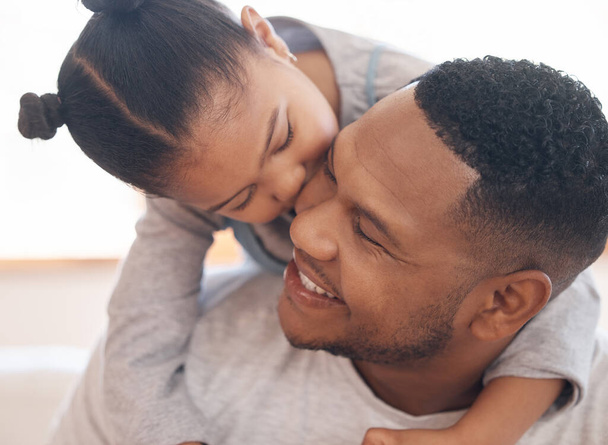 Closeup adorable little girl smiling and hugging her single father inside at home. Cute mixed race child enjoying weekend free time with single parent. Hispanic man bonding and holding his daughter. - 写真・画像