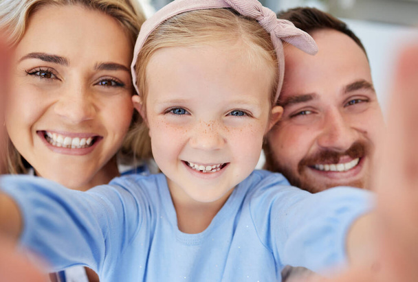 Closeup of adorable little preschool girl taking selfie with her parents . Loving parents posing with their daughter for self-portrait picture - 写真・画像