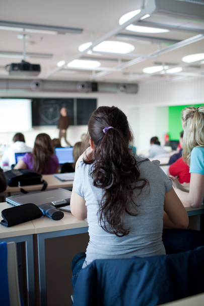 fiatal csinos női főiskolai hallgató ül egy osztályteremben teljes - Fotó, kép