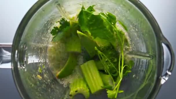 Elektromos turmixgép töltött nyers organikus zöldségeket készít friss vitamin smoothie szuper lassított felvétel közeli. Top view szeletelt zöldségek gyümölcs gyógynövények keverés üveg tál vegetáriánus koktél. - Felvétel, videó