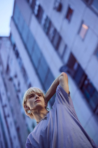 Un adolescente posa en el exterior urbano rodeado de edificios. - Foto, Imagen