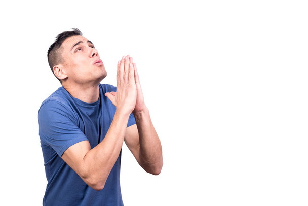 Studio portrait of a man looking up with hands together as praying in a white background - Foto, imagen