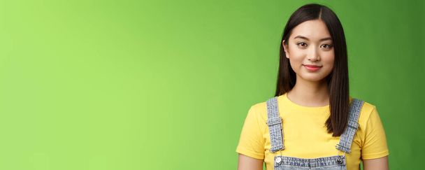 Waist-up friendly cheerful teenage asian college girl stand green background, smiling lovely, look tender amused, have relaxing casual conversation, packing things summer journey. Copy space - Photo, Image