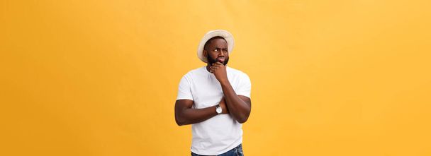 Human face expressions, emotions and feelings. Handsome young African American man looking up with thoughtful and skeptical expression, holding finger on his chin, trying to remember something - Photo, Image