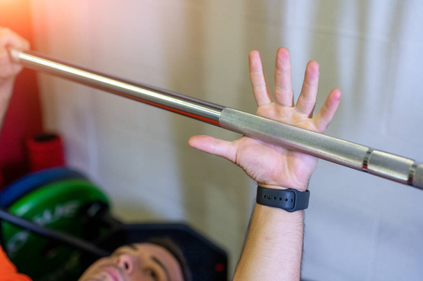 Conceptual image of hand grabbing the weight bar to start the bench press. In the blurred background the other hand is ready. Motivational photo. - Photo, Image