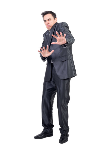 Full length of squeamish young man with dark hair in classy suit showing stop sign and making disgusting face while standing against white background - Foto, Bild
