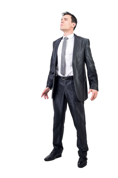 Volledig lichaam van waardige man in elegant pak op zoek naar afstand terwijl geïsoleerd op witte achtergrond in lichte studio - Foto, afbeelding