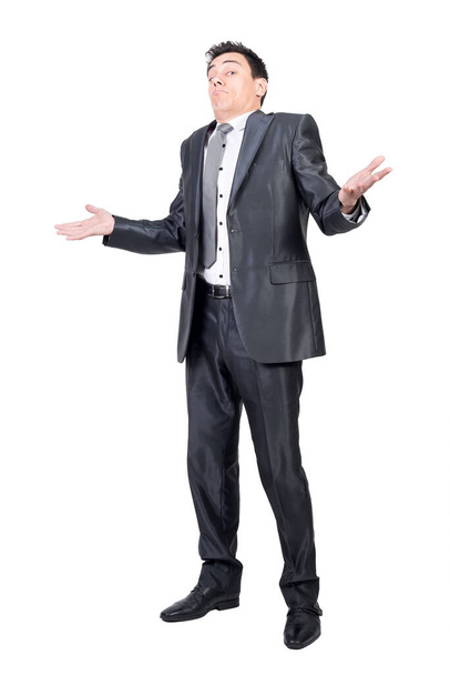 Full body of hesitant male in suit spreading arms and shrugging shoulders in bewilderment in studio against white background - Fotoğraf, Görsel