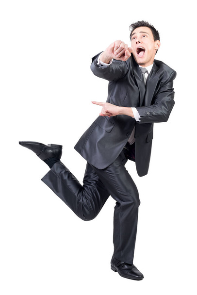 Volledig lichaam van gekke jonge mannelijke ondernemer met donker haar in formele outfit schreeuwen en weg te kijken tijdens het lopen tegen een witte achtergrond - Foto, afbeelding