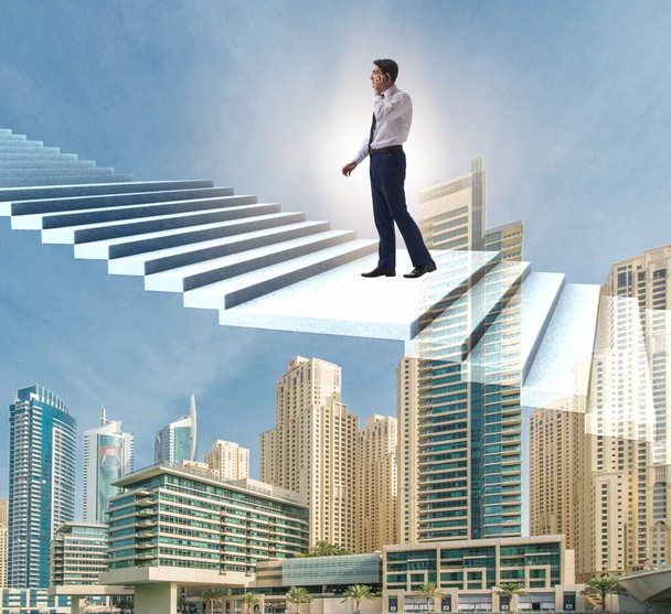 Бизнесмен поднимается по карьерной лестнице над городом - Фото, изображение