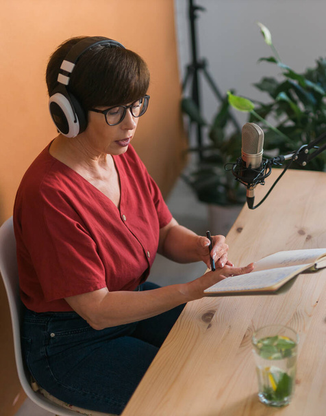 Портрет зрілої жінки в навушниках і розмовляє на онлайн радіостанції - подкаст і трансляція
 - Фото, зображення