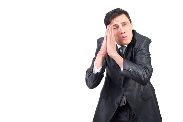 Ernsthafter erwachsener Mann in schwarzem Anzug fleht mit gefalteten Händen und blickt vor weißem Hintergrund in die Kamera - Foto, Bild