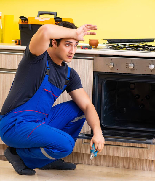 De jonge dienstverlener monteert keukenmeubilair - Foto, afbeelding