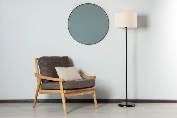 Stylish round mirror on white wall over armchair in room - Photo, Image