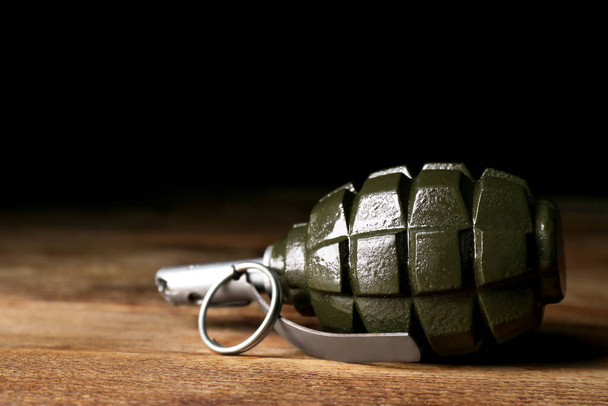 Hand grenade on wooden table against black background, closeup. Space for text - Zdjęcie, obraz