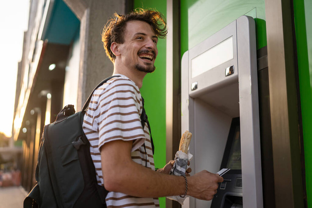 jeden człowiek młody dorosły nowoczesny tysiąclecia turysta za pomocą bankomatu do wycofania pieniędzy miejskich życie nowoczesne koncepcja życia stronie widok mężczyzna hold card kopia miejsca - Zdjęcie, obraz