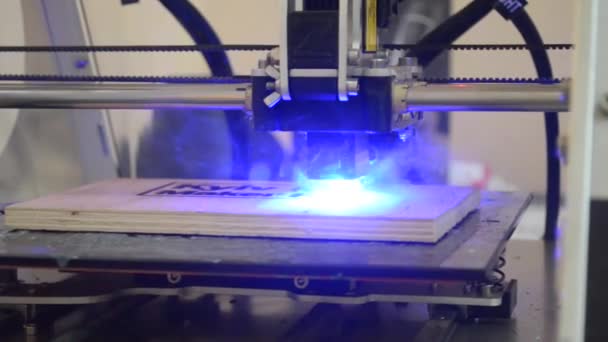 Λέιζερ χαρακτική στο ξύλο. 3D εκτυπωτής λέιζερ καίει το close-up μοτίβο σε ένα ξύλινο ταμπλό. Βιομηχανική σύγχρονο τεχνολογικό υπόβαθρο. Λέιζερ μπλε 3d εκτυπωτή που κινείται σε μια ξύλινη επιφάνεια εγκαύματα λέξεις - Πλάνα, βίντεο