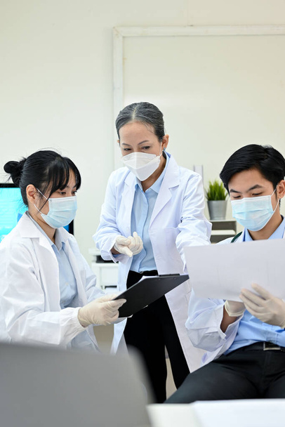 A professional and successful Asian senior female medical doctor specialist supervisor training and teaching two young Asian junior specialist in the lab. - Photo, Image