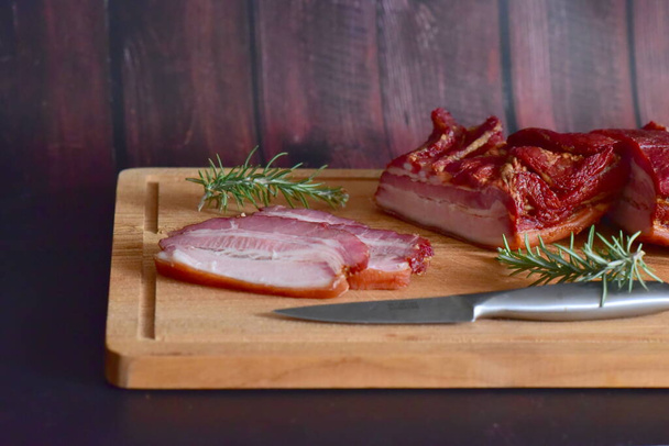 smoked meat with spices and herbs on wooden board - Foto, Imagen