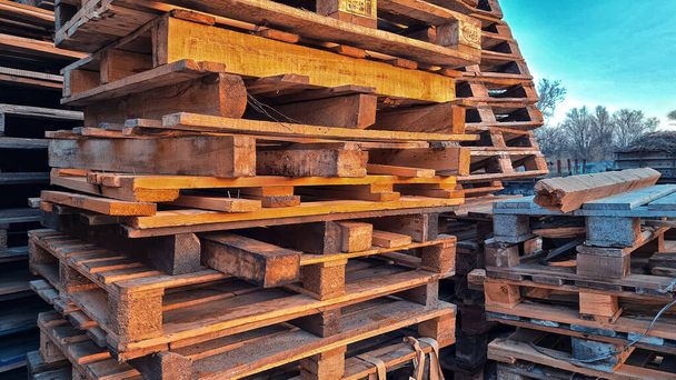 Muchas paletas de madera usadas antiguas se apilan al aire libre en el almacén de la empresa de entrega de carga. - Foto, Imagen