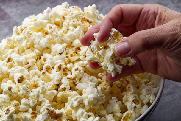 Weibliche Hand hält Popcorn auf grauem Betongrund. - Foto, Bild