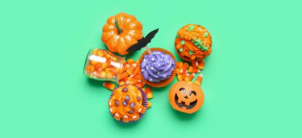Lekkere Halloween cupcakes en maïs snoepjes op groene achtergrond, bovenaanzicht - Foto, afbeelding
