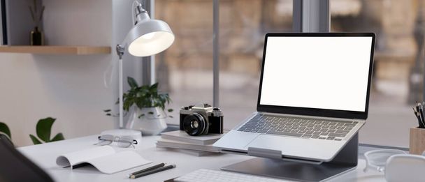 Современное офисное рабочее место с белым макетом ноутбука находится на подставке для ноутбука, настольной лампе, канцелярских принадлежностях и декоре. крупным планом. 3D рендеринг, 3D иллюстрация - Фото, изображение