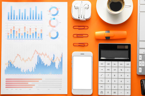 Business charts, gadgets and stationery on orange background - Photo, Image