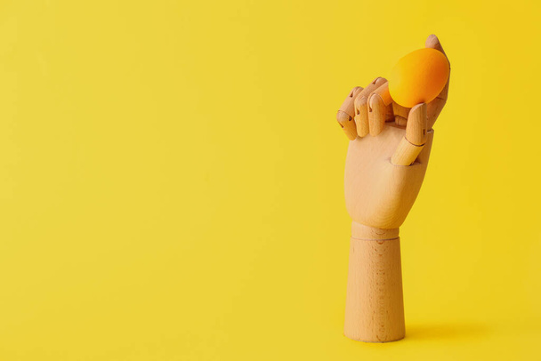 Дерев'яна рука з пасхальним яйцем на жовтому тлі
 - Фото, зображення