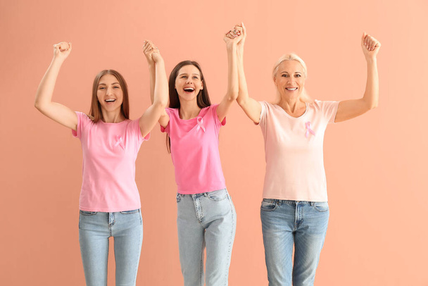 Mujeres felices con cintas de conciencia rosa sobre fondo de color. Concepto de cáncer de mama - Foto, imagen