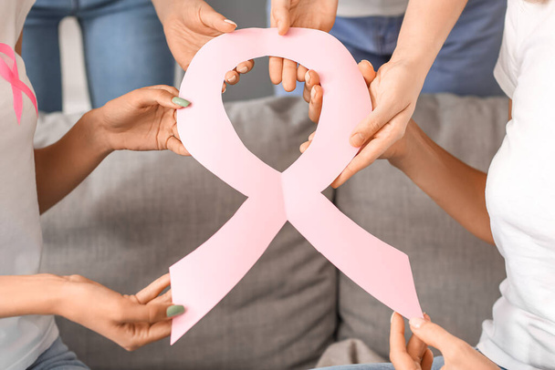 Beautiful women with pink awareness ribbon at home, closeup. Breast cancer concept - Photo, image
