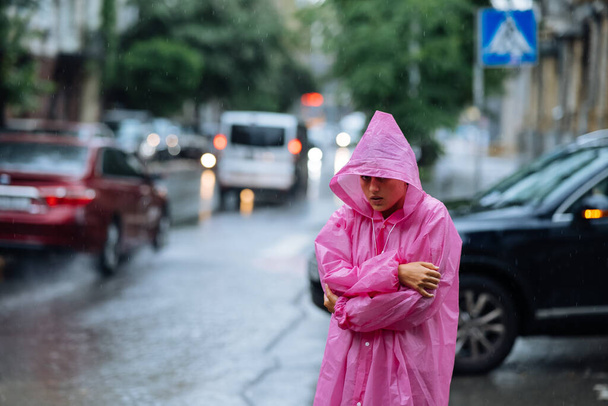 Surullinen nainen sadetakissa kadulla sateisena päivänä.. - Valokuva, kuva