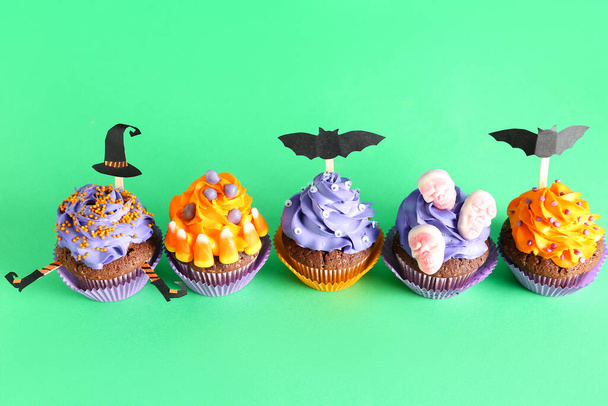 Tasty Halloween cupcakes on green background - Photo, Image