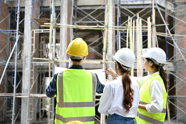 Na staveništi pracují a kontrolují budovu dvě profesionální asijské ženské inženýrky s mužským stavebním inspektorem. Koncept stavebního inženýra. pohled zpět - Fotografie, Obrázek