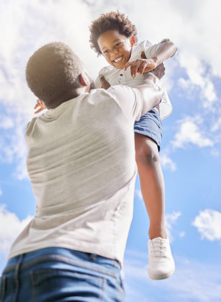 Los niños necesitan crecer con mucho amor. Bajo ángulo de tiro de un niño siendo levantado al cielo por su padre al aire libre - Foto, Imagen