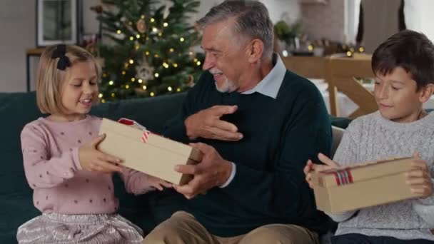 Nonno maggiore che condivide i regali di Natale con i bambini. Girato con telecamera ad elio rosso in 8K.   - Filmati, video