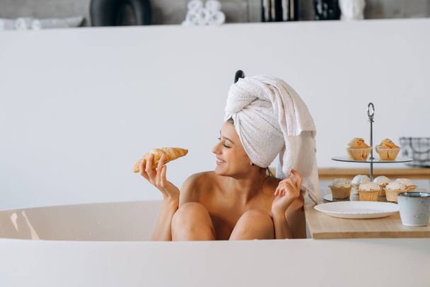 Fashion woman in the morning lying in the bath having breakfast - Foto, immagini