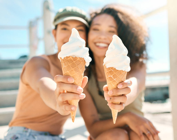 Care for a taste. Cropped portrait of two attractive young girlfriends enjoying ice creams on the beach - Fotoğraf, Görsel