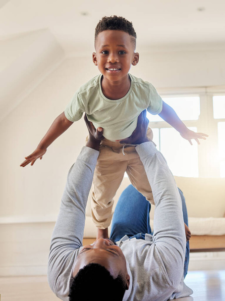 Sevimli küçük Afrikalı Amerikalı çocuk babasıyla birlikte evdeki oturma odasında oynuyor. Sevimli erkek çocuk içeride babasıyla gülümsüyor ve bağ kuruyor. Küçük oğluyla çok eğleniyor.. - Fotoğraf, Görsel