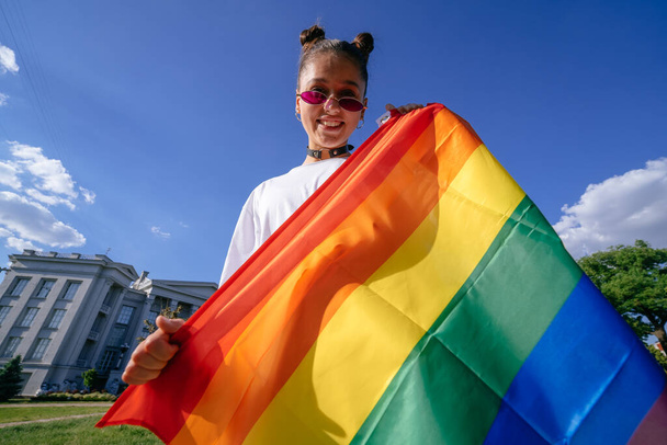 Молодая женщина с флагом гордости в парке. - Фото, изображение