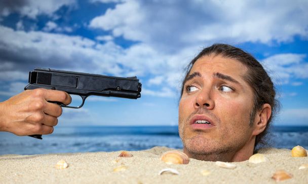 Egy férfi a fejéhez temetve a parton, pisztollyal a fejéhez szegezve. - Fotó, kép