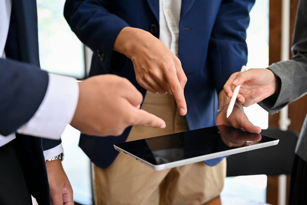 A group of professional and talented businesspeople pointed their fingers over the tablet screen to discuss and brainstorm their business strategy plan during the meeting. cropped image - Foto, Imagem
